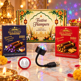A festive gift box, two snack boxes, a USB star light, and a silver coin are arranged on a marble surface with warm lighting.
