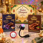 A festive hamper box, two boxes of wafer rolls, a USB star light, and a silver coin are arranged on a white surface with