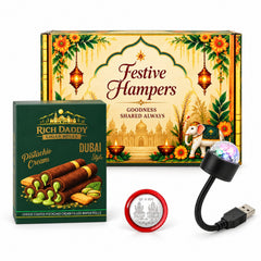 A festive hamper box, pistachio cream cigar rolls, a silver coin, and a USB galaxy light are arranged on a white surface.