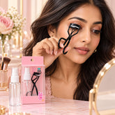 A woman with dark hair using a black eyelash curler with a white silicone pad, looking in a mirror.