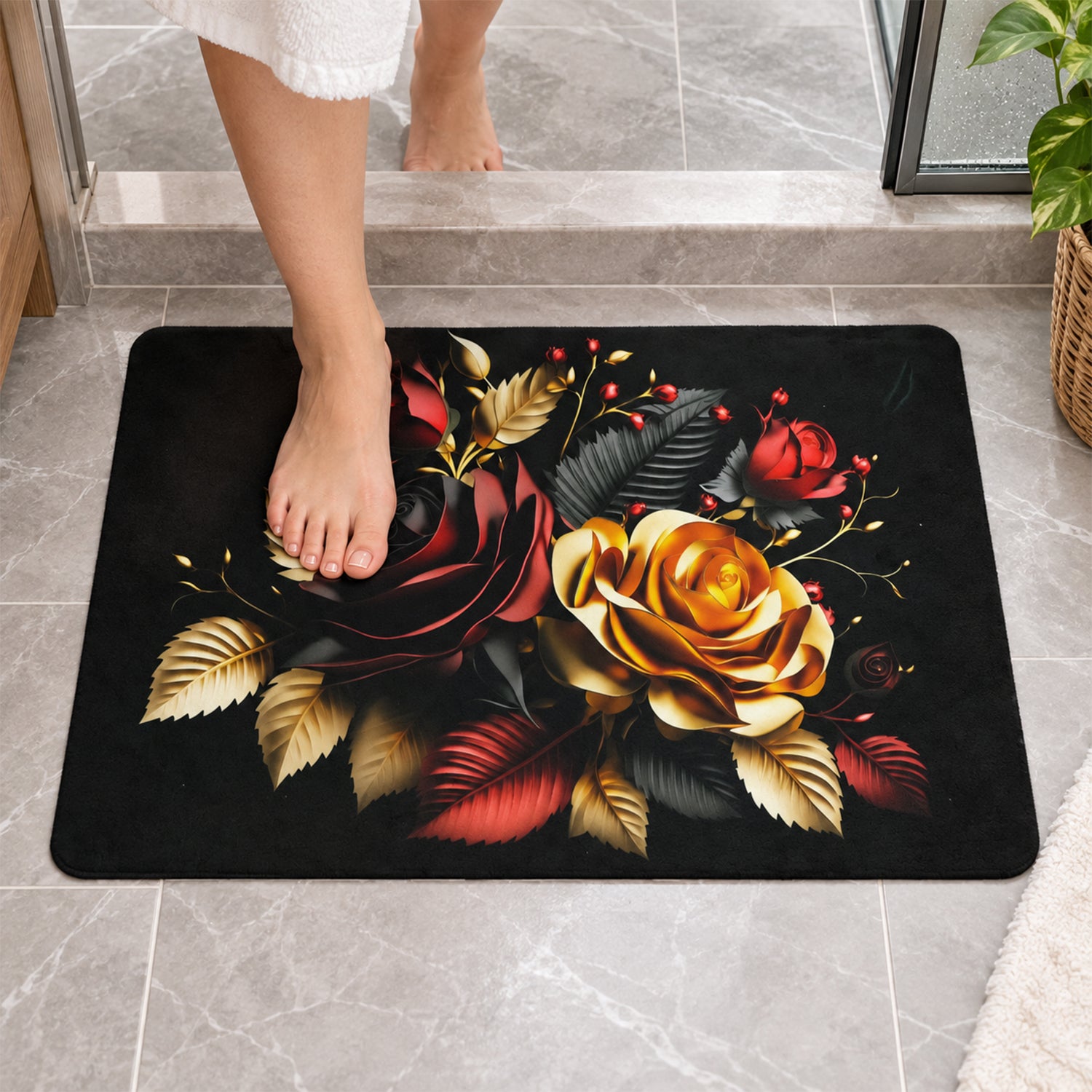 A person's bare feet step onto a rectangular black bath mat with a vibrant red and gold rose design.