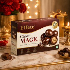 A box of Effete Choco Magic chocolates on a festive table with a lit candle, a golden gift, and scattered chocolate pieces.
