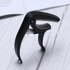 Capo and pick holder on guitar neck with instrument in background