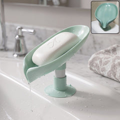 Green plastic leaf-shaped soap holder with suction cups mounted on bathroom tile