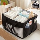 A black and white striped travel organizer bag caddy holds diapers, wipes, lotion, and a thermometer on a changing table.