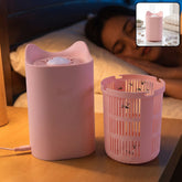 A pink cat-shaped mosquito killer lamp sits next to its removable collection basket, which contains several dead mosquitoes,