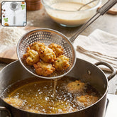 A stainless steel perforated skimmer spoon lifts golden fried fritters from hot oil in a metal pot.