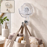 A clear octagonal self-adhesive wall hook with a silver hook, holding a beige tote bag filled with towels and toiletries, on
