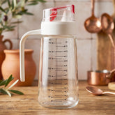Glass Oil Dispenser Bottle 500ml with Auto-Flip Red Cap, White Side Handle and ml/oz Measurement Scale on Kitchen Counter