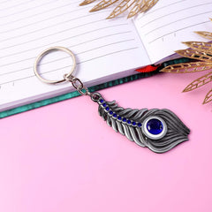 Silver-toned metal peacock feather keychain on white