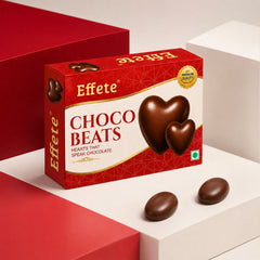 A red and white box of Effete Choco Beats chocolates sits on a white and red geometric background with two candies.