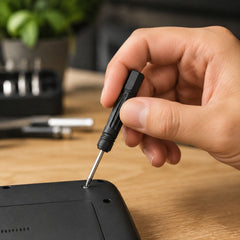 A hand uses a black and silver mini screwdriver to tighten a screw on a black device, with a small inset showing â€“ view 3