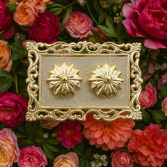 A gold rectangular pooja thali with two flower-shaped containers, surrounded by red and orange flowers.
