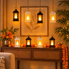 Eight small black and white lanterns with glowing LED candles are arranged on a wooden console table and hanging above it,