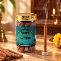 A clear jar of brown dhoop sticks with a gold lid, one stick burning in a small holder.