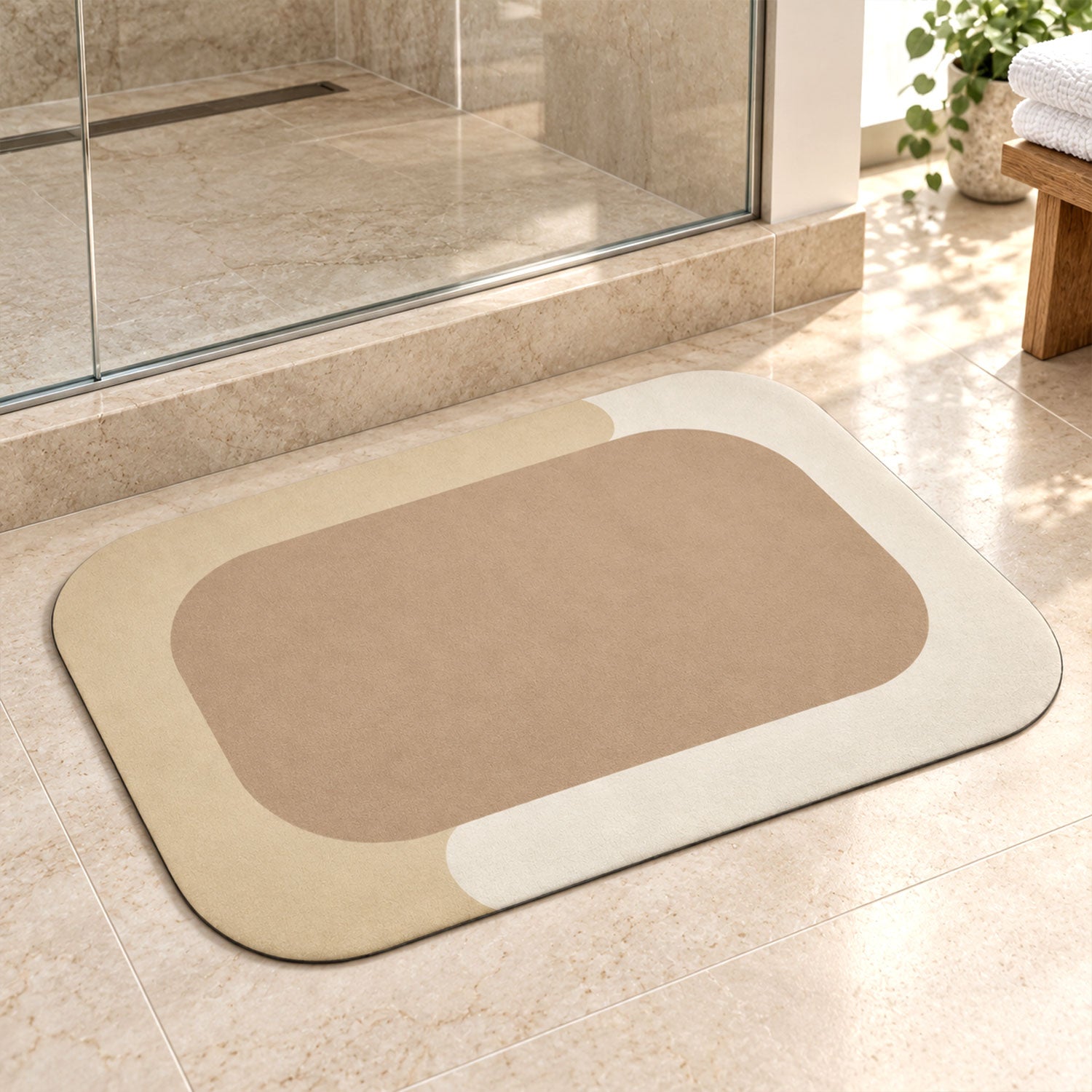 A rectangular bath mat with rounded corners, featuring a beige center and a light cream border, rests on tiled floor next to