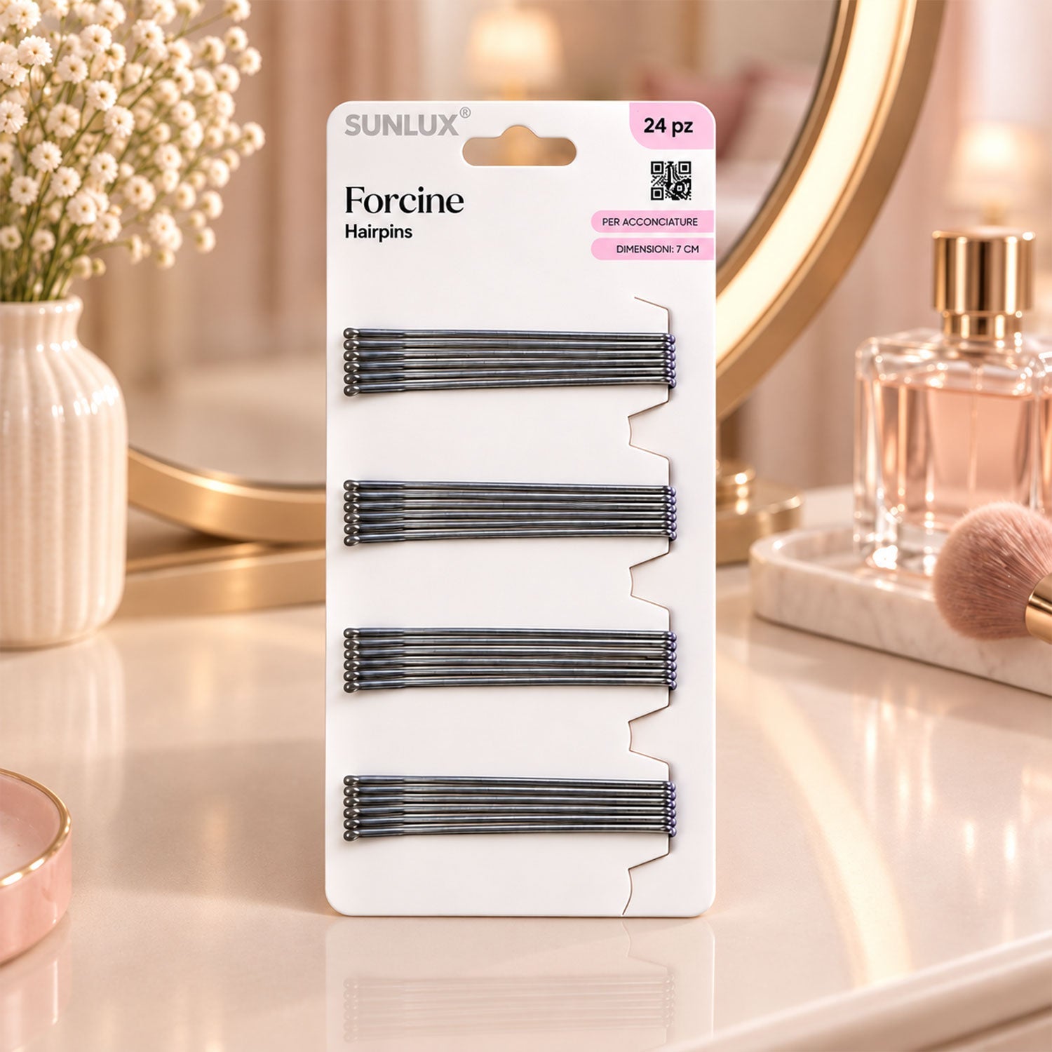 A white package of twenty-four silver hairpins on a vanity, with a mirror, vase of flowers, and a makeup brush.