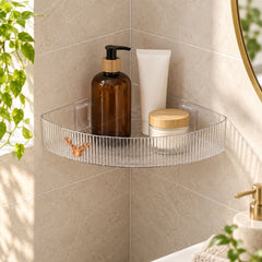 Clear ribbed corner shelf with amber pump bottle, white tube, and cream jar on a tiled wall.