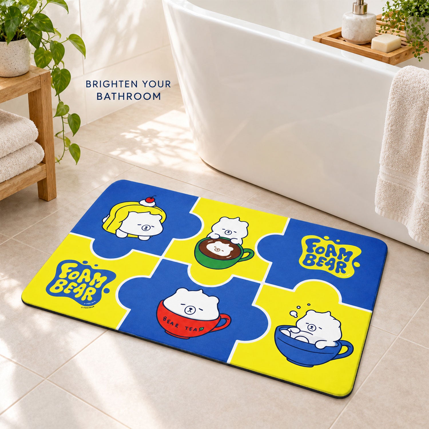 A blue and yellow bath mat with cartoon bears in cups lies on a tiled bathroom floor next to a white tub.