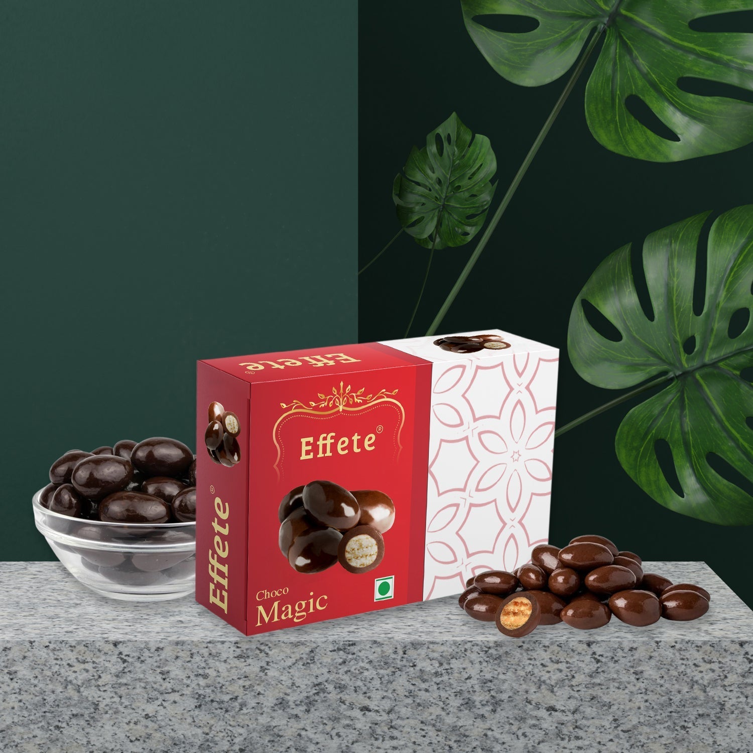 Effete Choco Magic box with chocolate-covered nuts in a bowl and on the surface, set against a dark green background with
