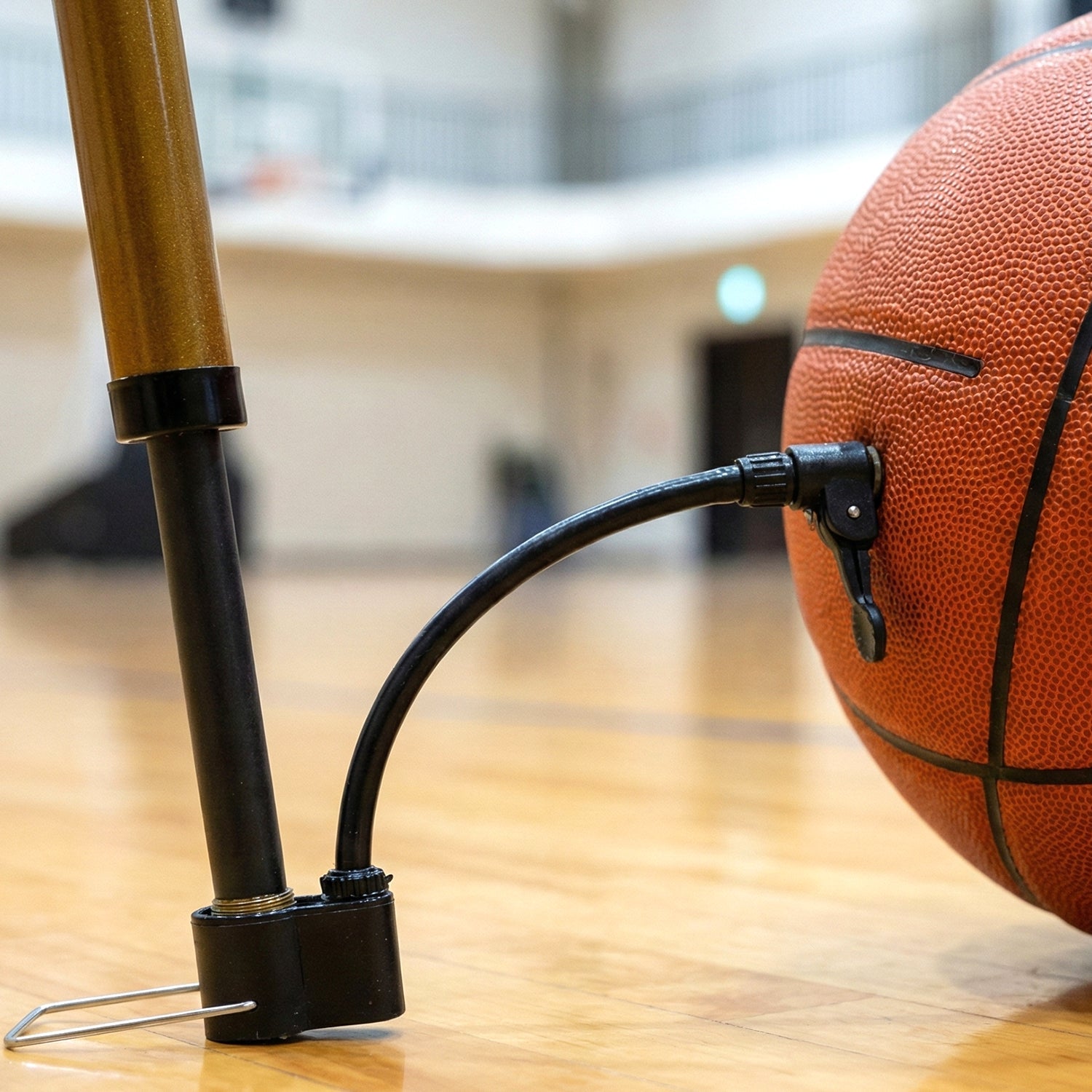 Mini hand air pump with attached needle inflating a basketball