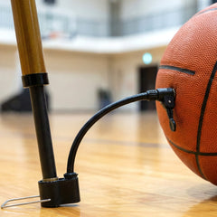 Mini hand air pump with attached needle inflating a basketball