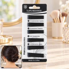 A woman's dark hair is styled in a low bun with two black U-pins securing it, on a vanity surface.