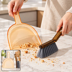 A person sweeps crumbs into an amber dustpan with a dark brown brush on a light counter, with a small inset of the set.