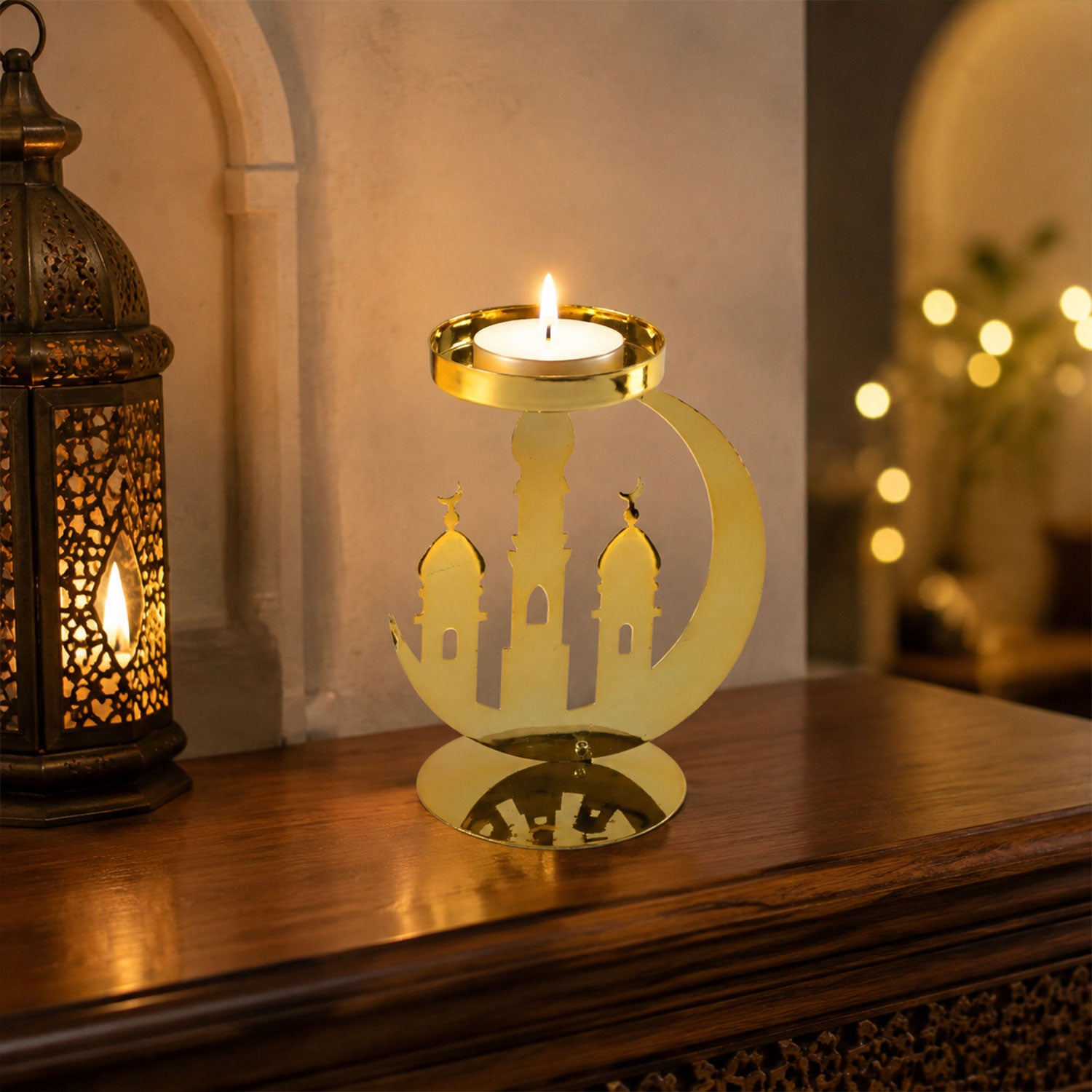 A golden metal incense holder with a crescent moon and mosque design, holding a lit tealight candle on a wooden surface