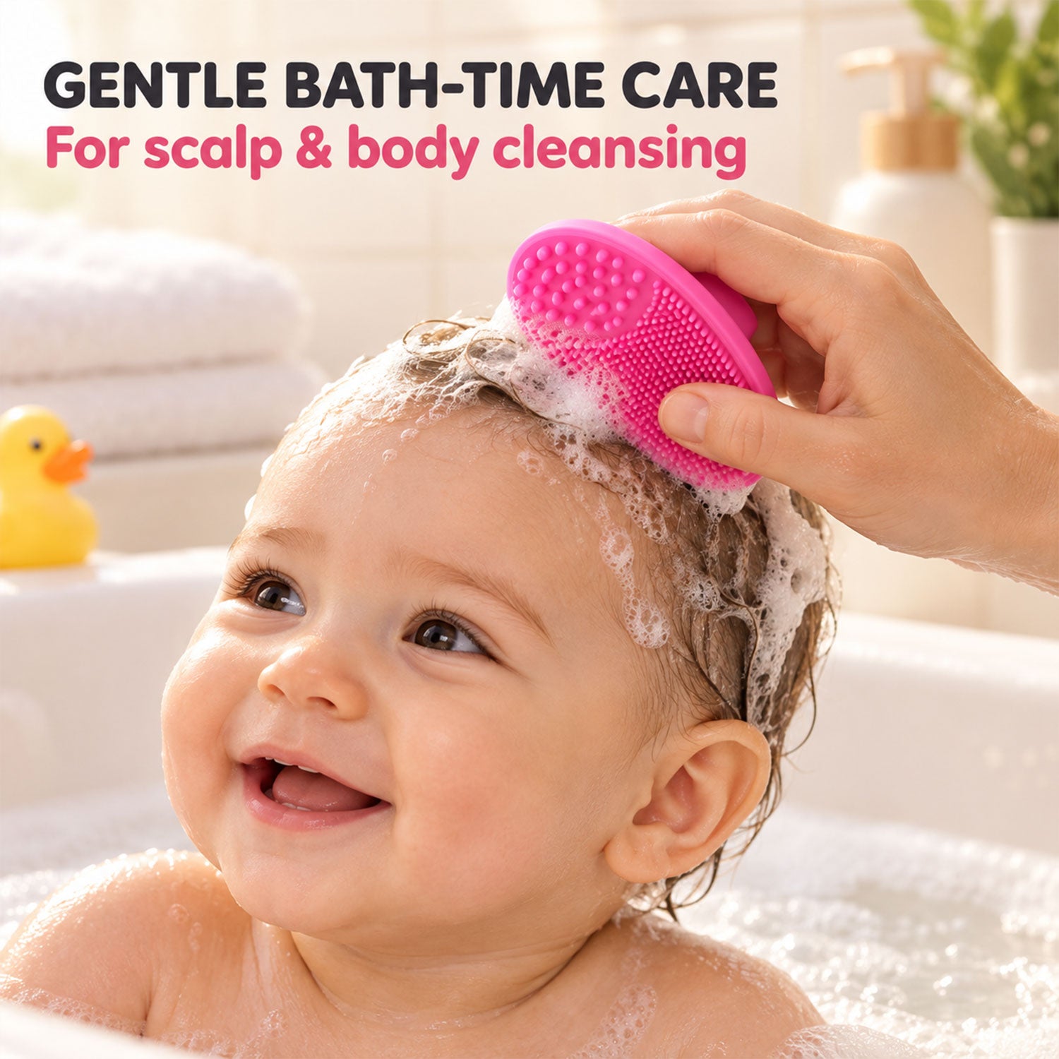 A smiling baby in a bubble bath has their hair gently brushed with a pink silicone scrubber by an adult's hand.