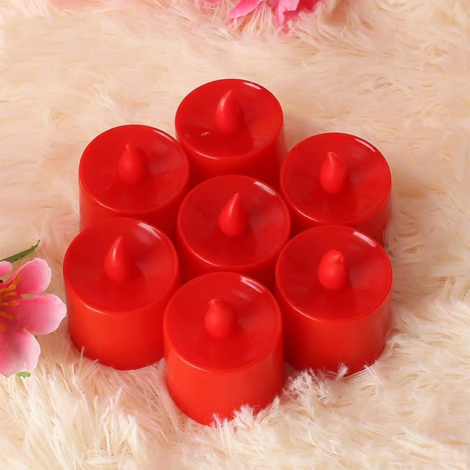 Red LED tea light diya on a dark surface, casting a warm, inviting glow.