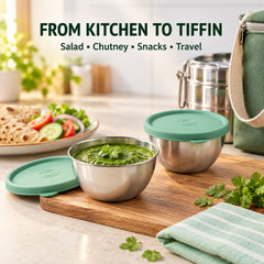 Two stainless steel bowls with green lids, one open with chutney, on a wooden board in a kitchen setting.