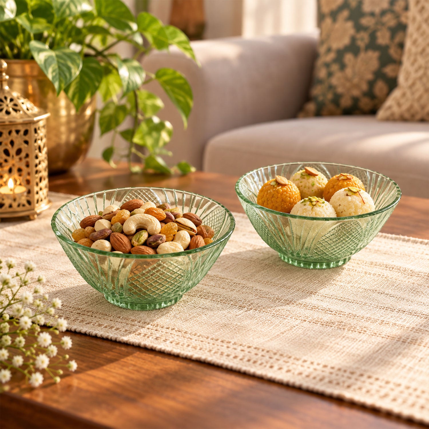 Two green glass bowls filled with nuts and sweets on a patterned table runner, with a golden lantern nearby.