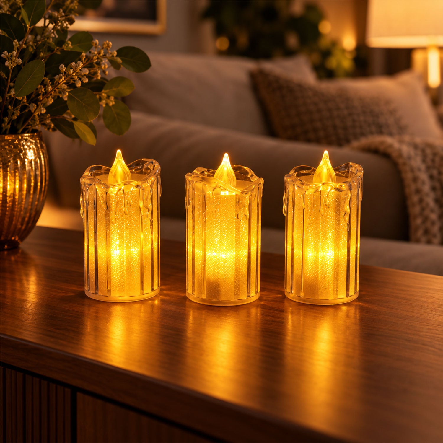 Three clear plastic LED candles emitting a bright yellow light, positioned on a dark wooden surface in a cozy room setting.