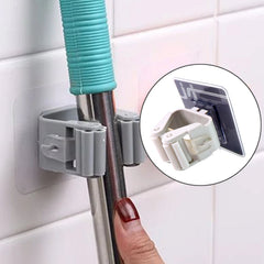 Multiple adhesive mop & broom holders on a wall organizing various tools