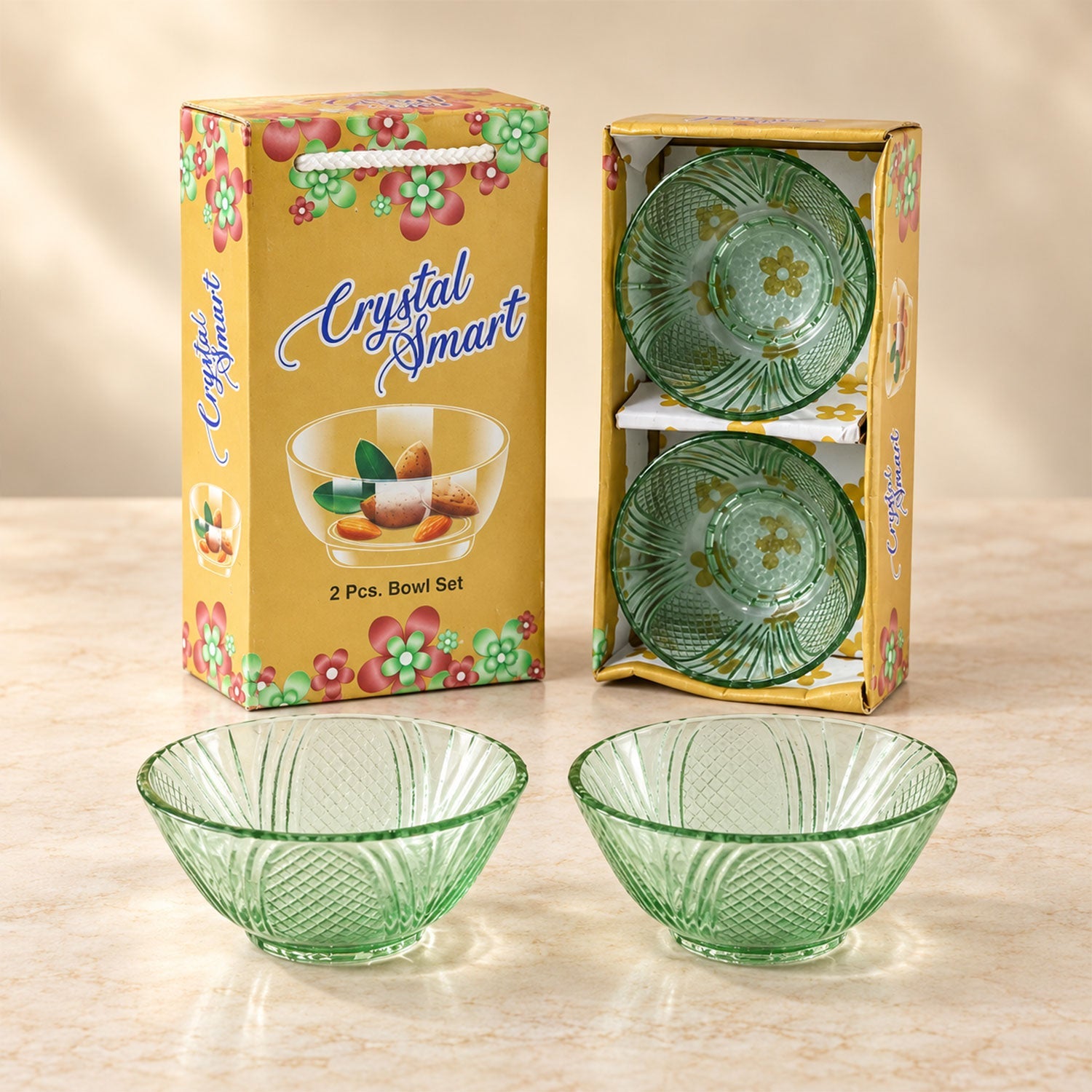 Two green glass bowls, one in its yellow packaging and two bowls on the table. The packaging has a floral design.
