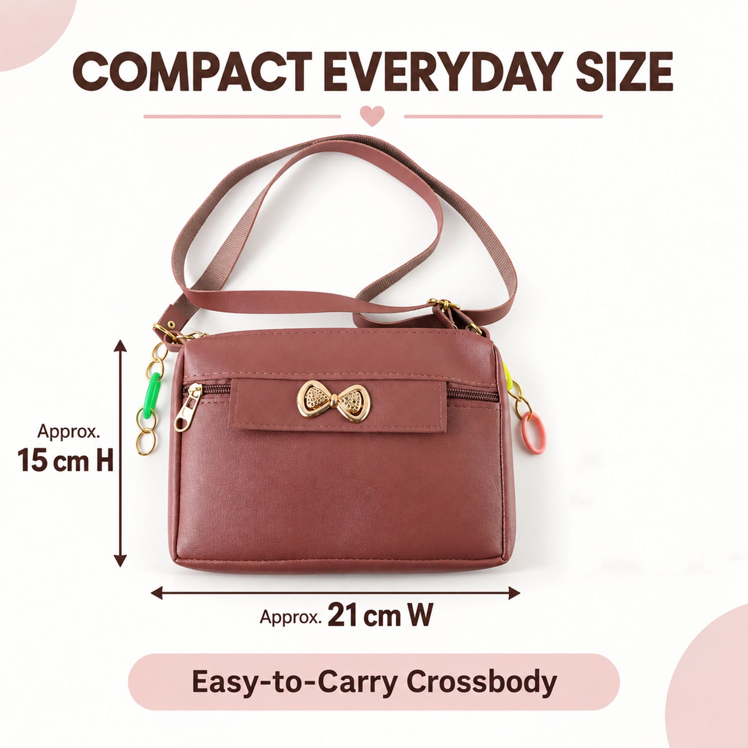 A mauve sling bag with a gold bow and colorful charms, showing approximate dimensions of 15cm H x 21cm W.
