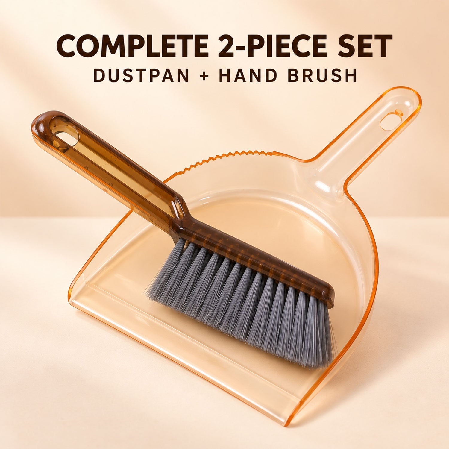 An amber plastic dustpan and a dark brown hand brush with gray bristles are positioned together on a light peach background.