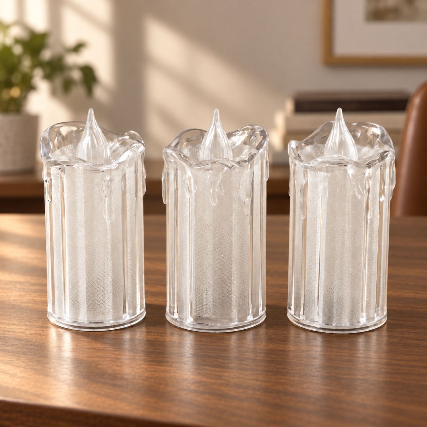 Three clear plastic LED candles, unlit, with a textured design, sitting on a polished wooden table in a well-lit room.