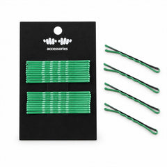 A black card with green metal bobby pins lies next to four individual green pins on a plain white background.