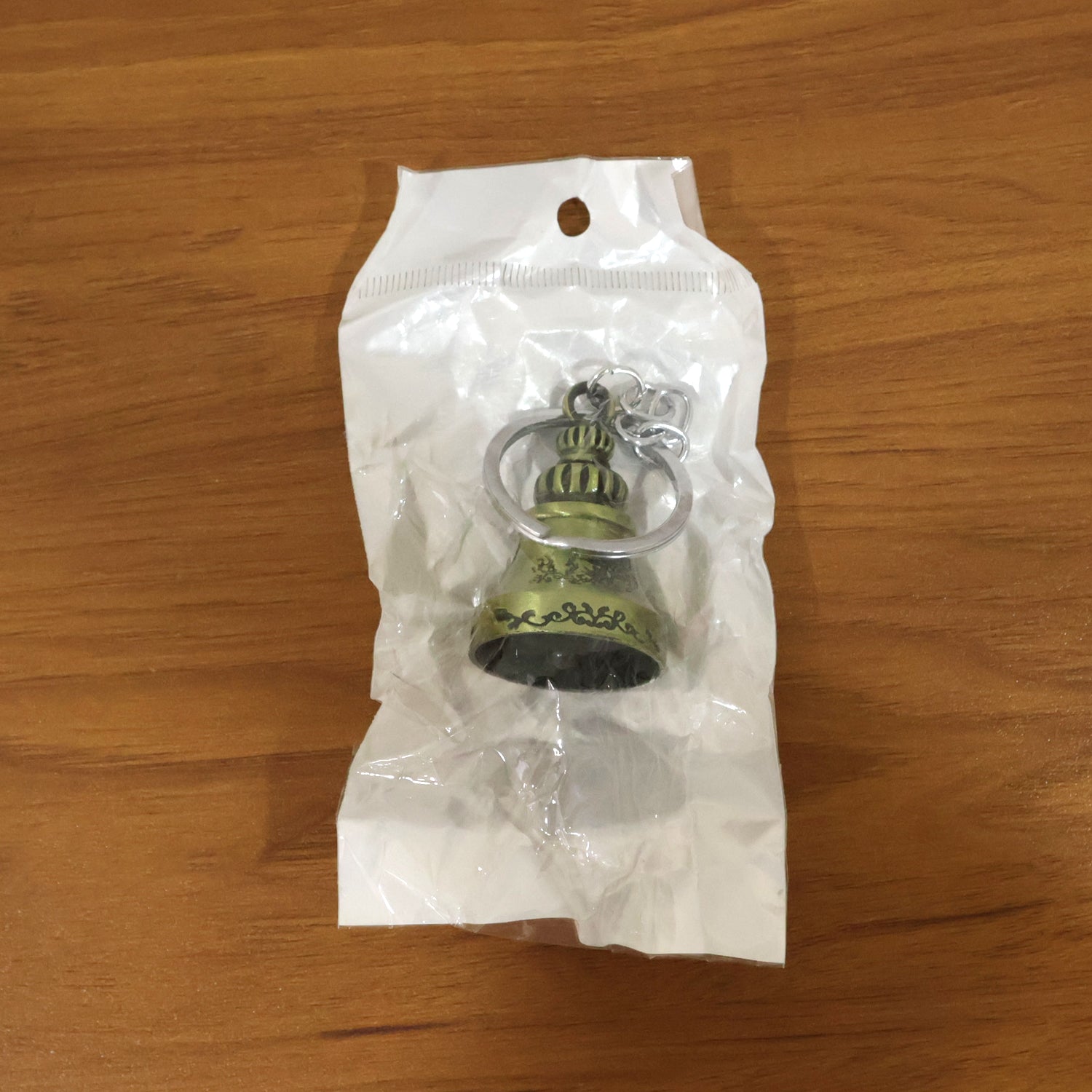 Metal temple bell keychain on textured background