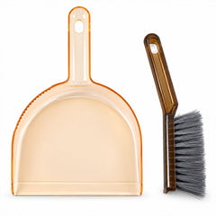 An amber plastic dustpan and a dark brown hand brush with gray bristles are arranged side by side on a plain white