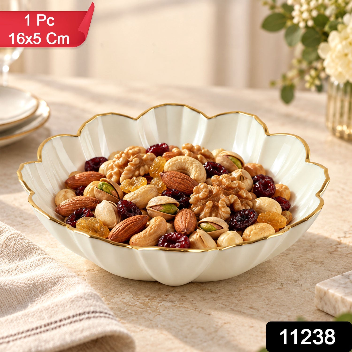 White ceramic scalloped bowl with a gold rim filled with mixed nuts and dried fruits on a light table. â€“ view 2