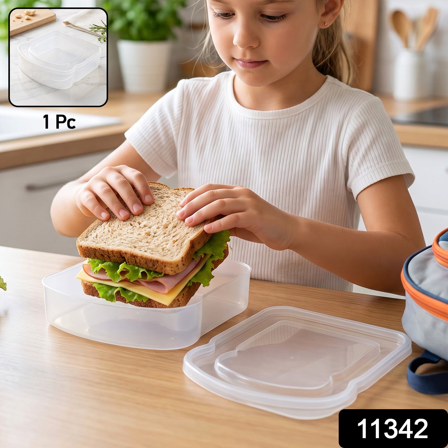 A clear plastic sandwich container with a lid rests on a marble surface with herbs and a cutting board in the background.