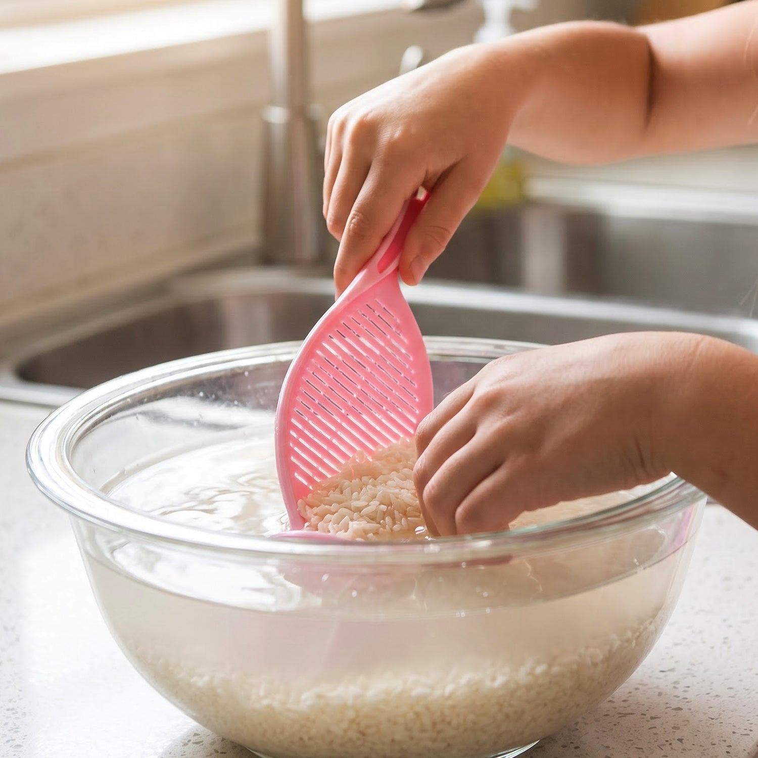 Strainer spoon rinsing rice under a tap