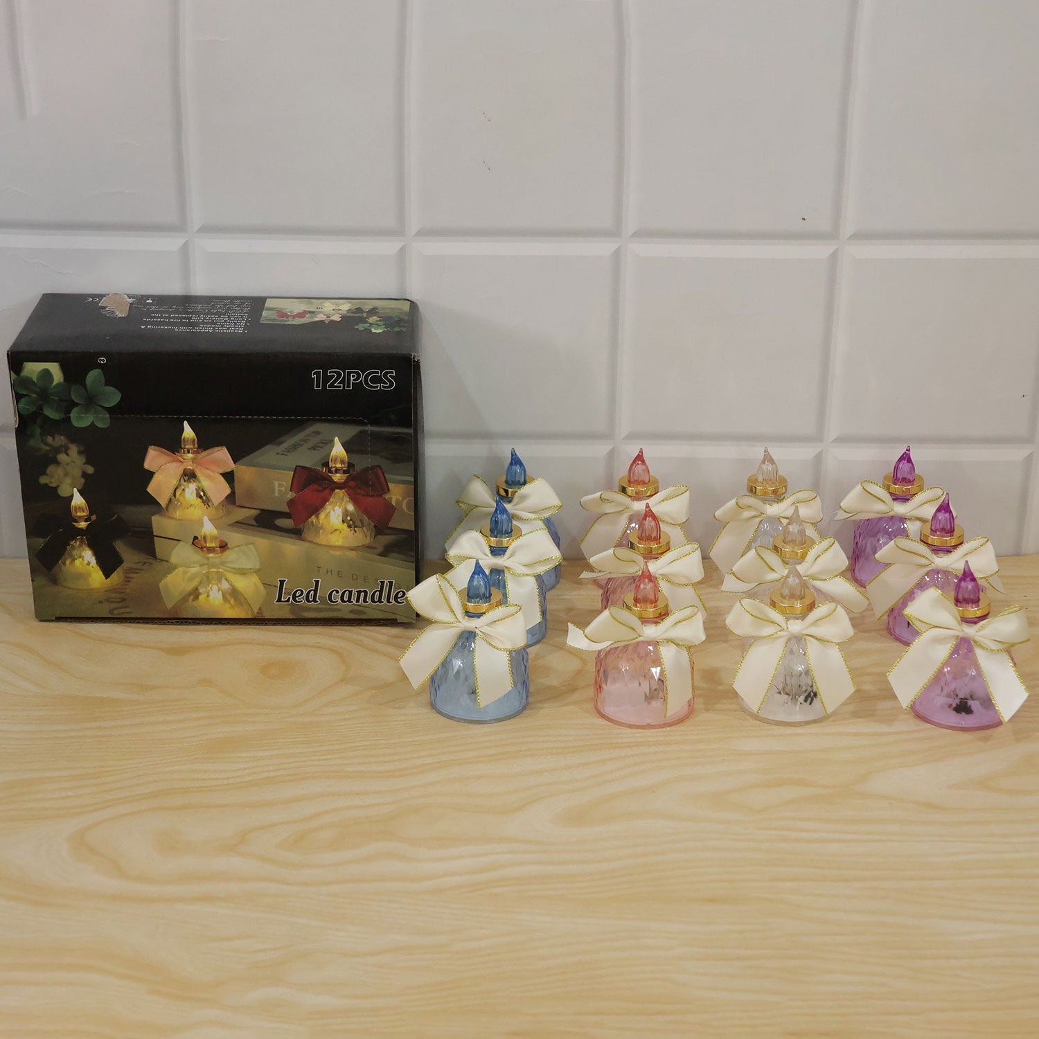 Flameless LED candles with bows used as elegant decor on a shelf with other items