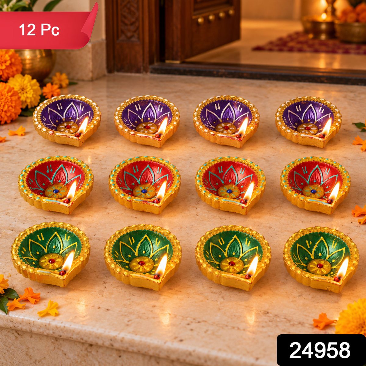 Twelve lit clay diyas in three distinct colors with gold rims, on a stone step with scattered flowers.