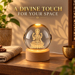 A radiant crystal ball lamp with a detailed Laxmi engraving, resting on a wooden base, in a softly lit setting.