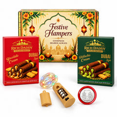 A festive gift box, two wafer roll boxes, fairy lights with a battery pack, and a silver coin are displayed on a white