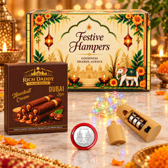 Festive hamper box with wafer rolls, string lights, and a silver coin on a marble surface.